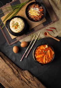 A vertical high angle shot of bowls od hummus, vegetables, and soup on a black table